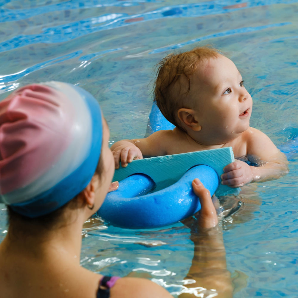 Mutter hilft Baby beim Schwimmen