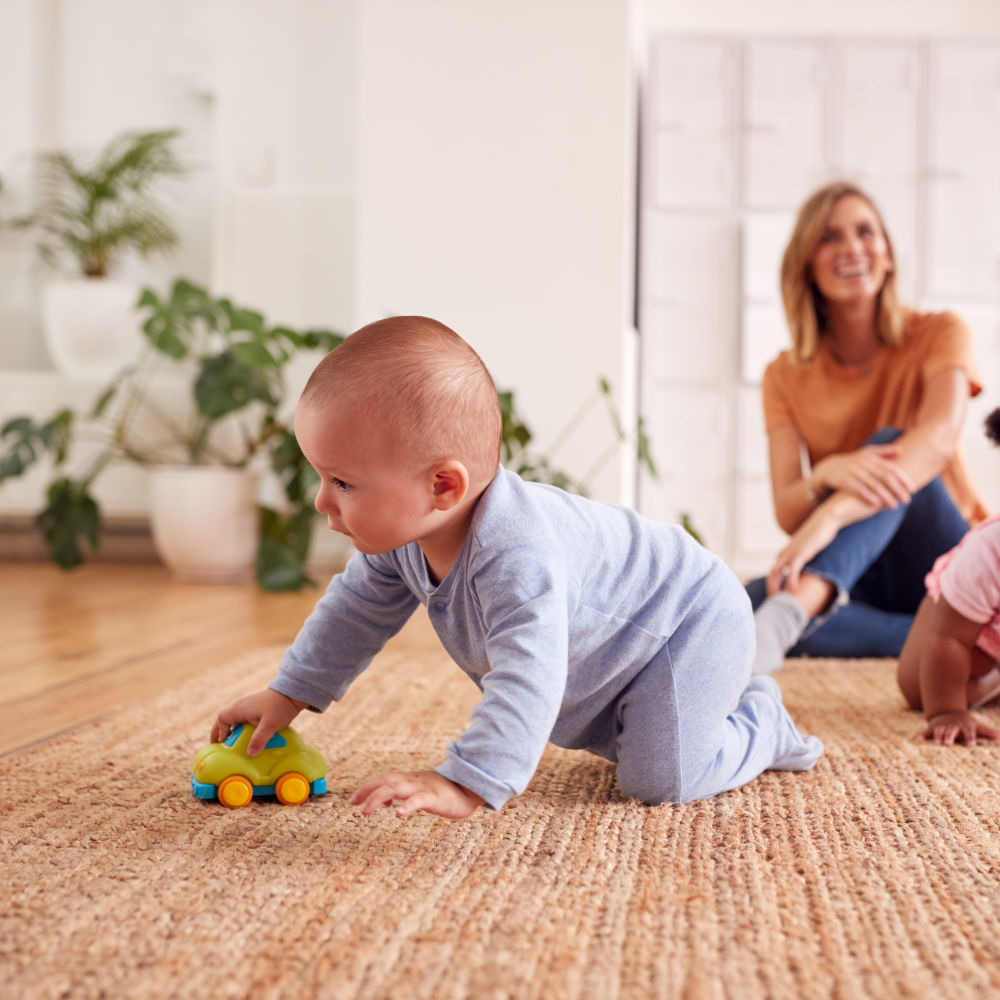 Mutter spielt mit Baby beim Krabbeln