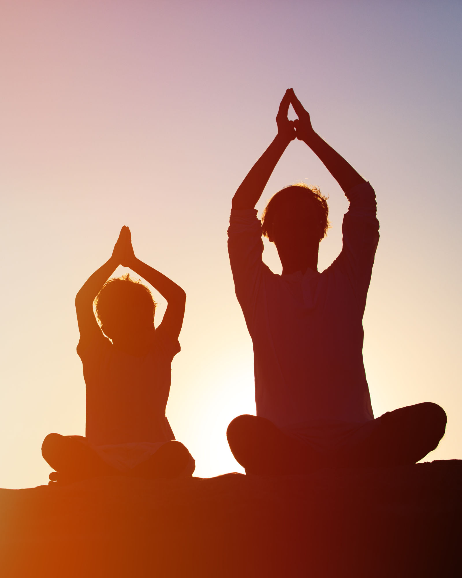 Zwei Personen üben gemeinsam Yoga im Sonnenuntergang